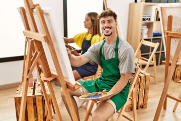 Young hispanic artist couple smiling happy drawing at art studio.