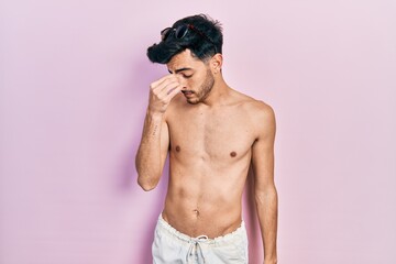 Fototapeta premium Young hispanic man wearing swimwear shirtless tired rubbing nose and eyes feeling fatigue and headache. stress and frustration concept.