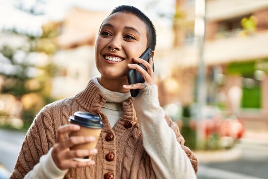 Young hispanic woman with short hair smiling happy drinking a cup of coffee and talking on the phone