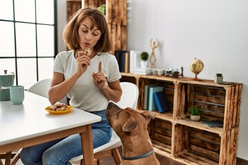 Young caucasian woman teaching dog prohibition eat cookies at home