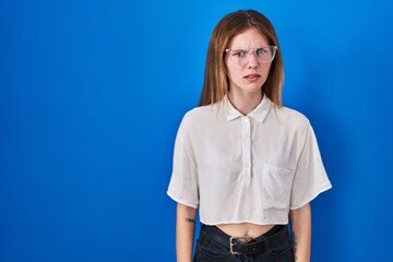 Beautiful woman standing over blue background skeptic and nervous, frowning upset because of...