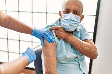 Senior man with safety mas getting vaccinated with covid 19 immunity vaccine, nurse injecting...