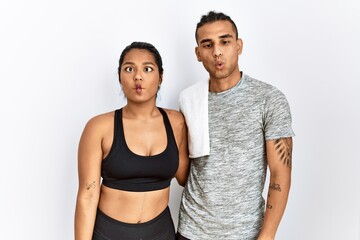 Fototapeta na wymiar Young latin couple wearing sportswear standing over isolated background making fish face with lips, crazy and comical gesture. funny expression.
