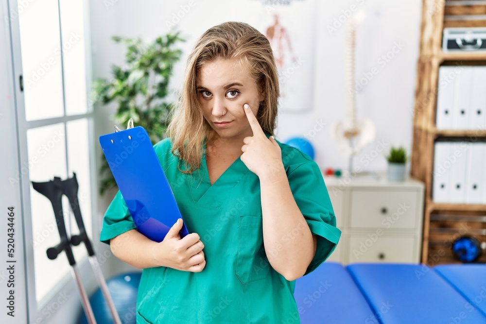 Sticker Young caucasian woman working at pain recovery clinic pointing to the eye watching you gesture, suspicious expression