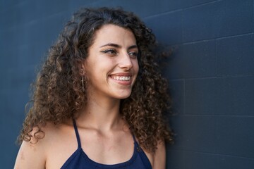 Young beautiful hispanic woman smiling confident looking to the side over isolated black background