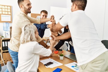 Obraz premium Group of business workers smiling happy celebrating making tower with fists together at the office.