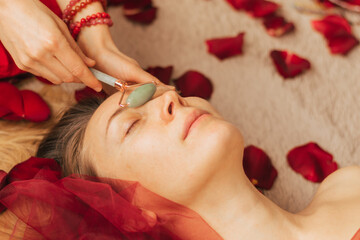 Obraz na płótnie Canvas A woman makes a gouache massage with a jade roller. Mental health care, meditation and relaxation