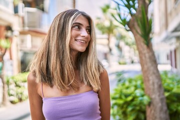 Young blonde girl smiling happy standing at the city.