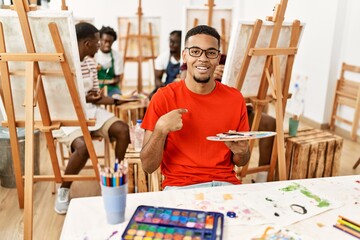 Young african man at art studio pointing finger to one self smiling happy and proud