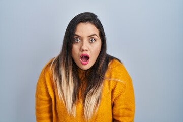 Young hispanic woman standing over isolated background afraid and shocked with surprise and amazed expression, fear and excited face.