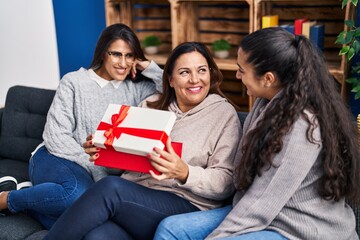 Three woman surprise with gift sitting on sofa at home