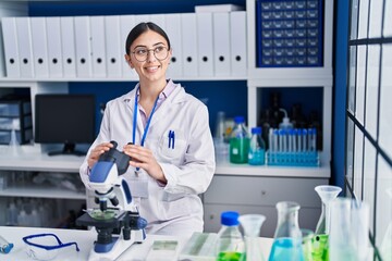 Young hispanic woman scientist using microscope at laboratory