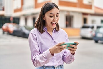 Young hispanic woman smiling confident using smartphone at street