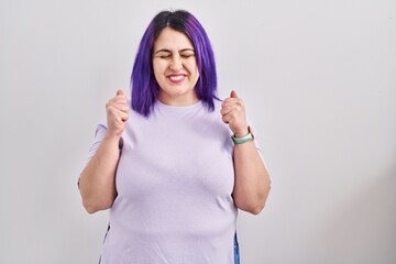 Fototapeta na wymiar Plus size woman wit purple hair standing over isolated background excited for success with arms raised and eyes closed celebrating victory smiling. winner concept.