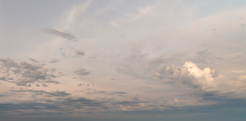 Beautiful cloudscape wide angle panorama sky replacement background with layers of colorful white, yellow, orange and blue cumulus clouds.