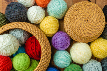 Yarn in a basket. Colorful balls of wool on wooden table. Variety of yarn balls, view from above.