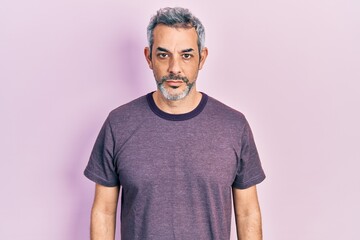 Handsome middle age man with grey hair wearing casual t shirt with serious expression on face. simple and natural looking at the camera.