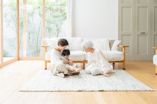 リビングにいる笑顔の親子とおばあちゃん（家族・ファミリー・育児・子育て・孫・おばあちゃん・帰省）