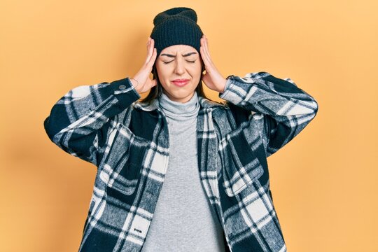 Beautiful woman with blue eyes wearing wool cap with hand on head, headache because stress. suffering migraine.