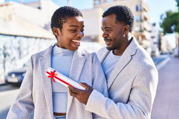 Man and woman couple standing together surprise with gift at street