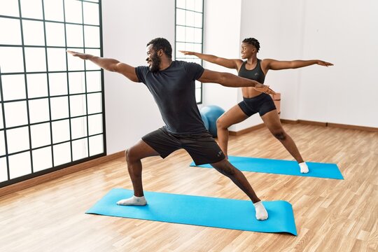 Young african american sporty couple smiling happy training yoga at sport center.
