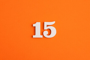 White wooden number 15 on eva rubber orange background