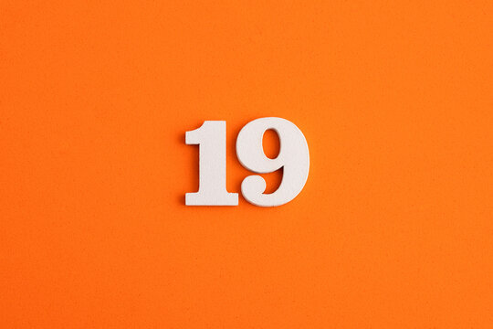 White wooden number 19 on eva rubber orange background
