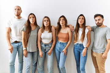 Group of young friends standing together over isolated background making fish face with lips, crazy and comical gesture. funny expression.