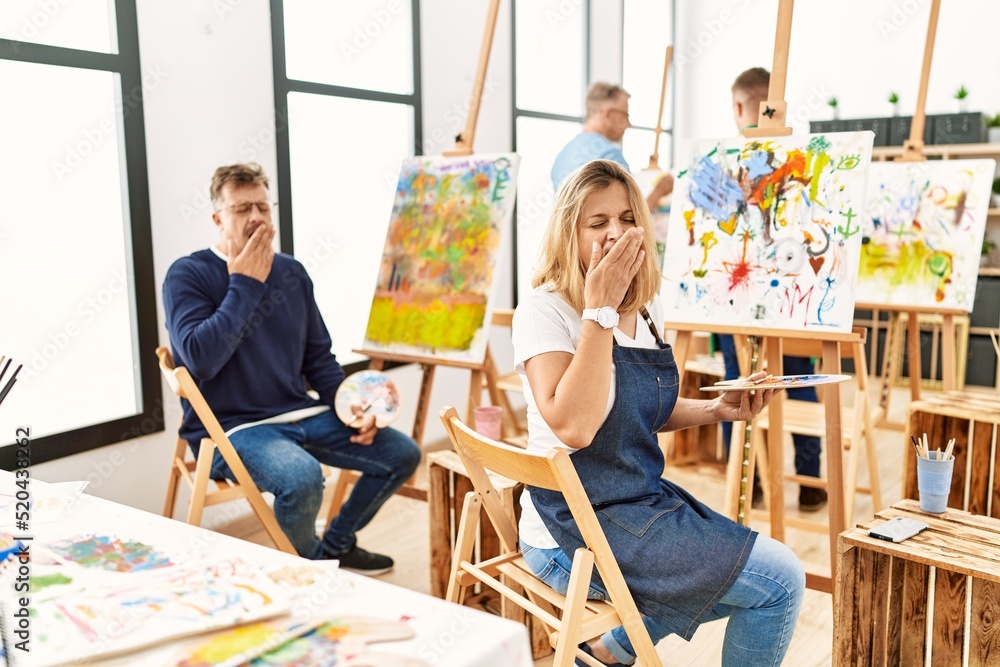 Poster group of middle age artist at art studio bored yawning tired covering mouth with hand. restless and 