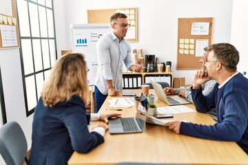 Group of middle age business workers listening boss speech during meeting at the office.