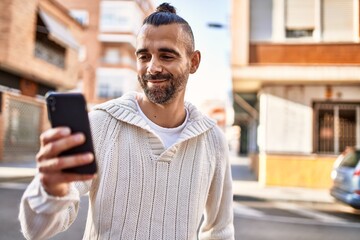 Handsome middle age man with beard standing happy and confident outdoors using smartphone