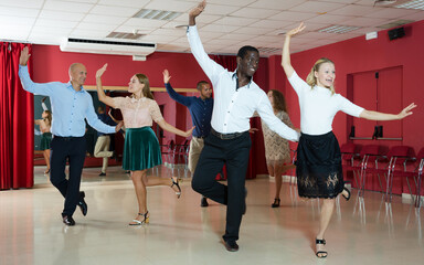 Fototapeta premium Couples of young people practicing twist movements together at modern dance studio