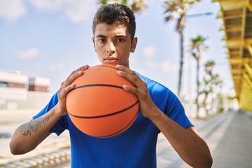 Fototapeta premium Young hispanic man training with basketball ball outdoors