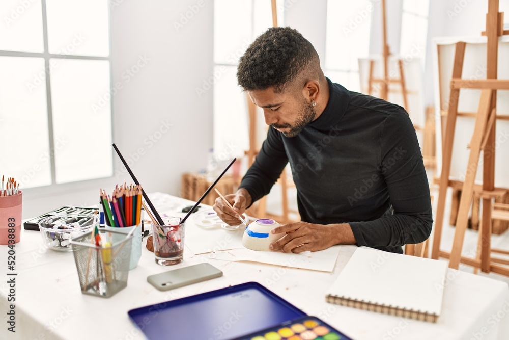 Poster young african american artist man concentrated painting pottery at art studio.