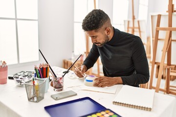 Young african american artist man concentrated painting pottery at art studio.