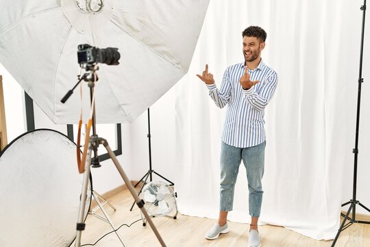 Arab young man posing as model at photography studio showing middle finger doing fuck you bad expression, provocation and rude attitude. screaming excited