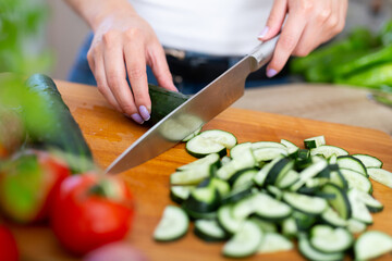 Female hands cuts vegetables on cutting board at cook table