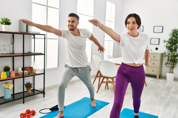 Young hispanic couple doing yoga at home