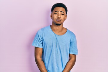 Young african american man wearing casual blue t shirt puffing cheeks with funny face. mouth inflated with air, crazy expression. - obrazy, fototapety, plakaty