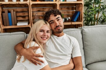 Young beautiful couple sitting on the sofa and hugging at home.