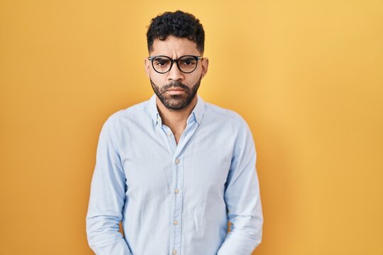 Hispanic man with beard standing over yellow background skeptic and nervous, frowning upset because of problem. negative person.