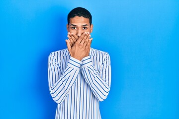 Young african american guy wearing casual clothes shocked covering mouth with hands for mistake. secret concept.