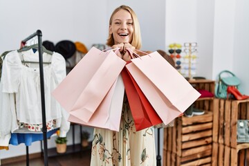 Young blonde woman holding shopping bags at clothing store