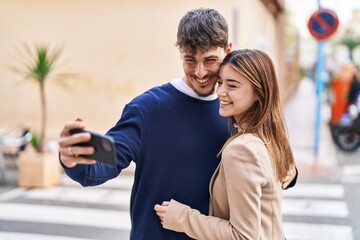 Mand and woman couple hugging each other make selfie by smartphone at street