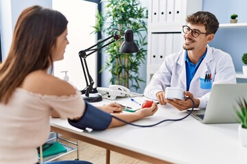 Man and woman wearing doctor uniform having medical consultation using tensiometer at clinic