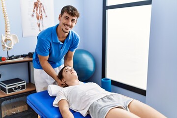 Man and woman wearing physiotherpy uniform having reiki therapy session at clinic