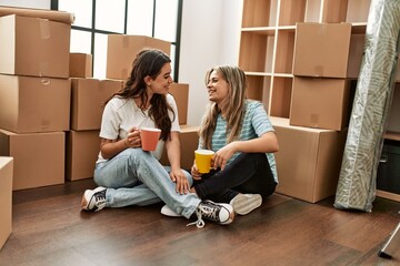Young couple smiling happy drinking cup of coffee at new home.