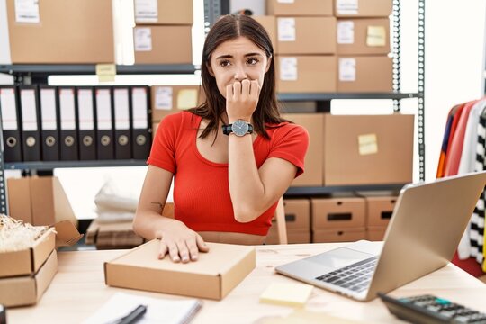 Young hispanic woman preparing order working at storehouse looking stressed and nervous with hands on mouth biting nails. anxiety problem.