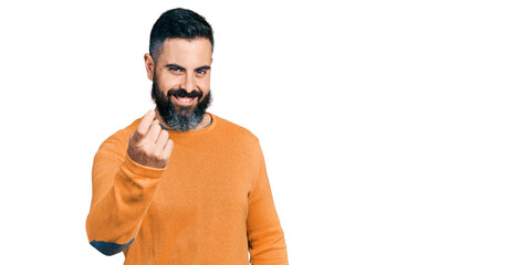 Fototapeta premium Hispanic man with beard wearing casual winter sweater beckoning come here gesture with hand inviting welcoming happy and smiling