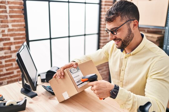 Young hispanic man ecommerce business worker scanning label using barcode reader at office
